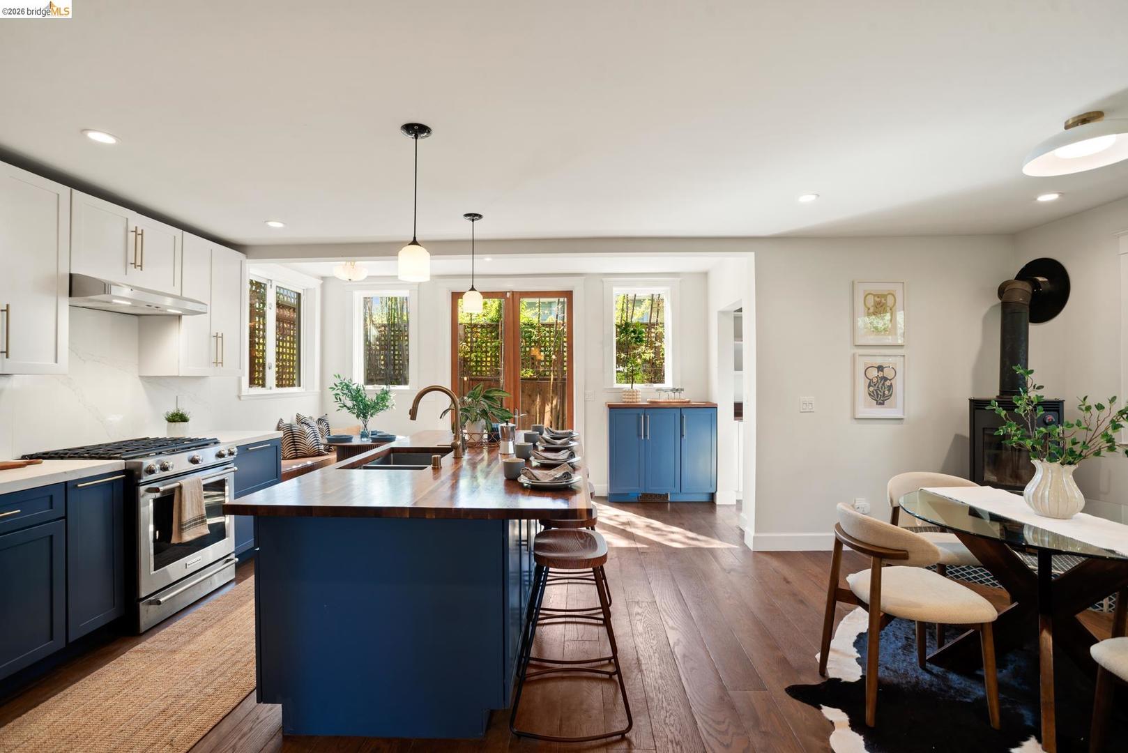 6145 Fremont Street, North Oakland — open kitchen with navy cabinets and a butcher-block island, looking back to French doors and the dining area