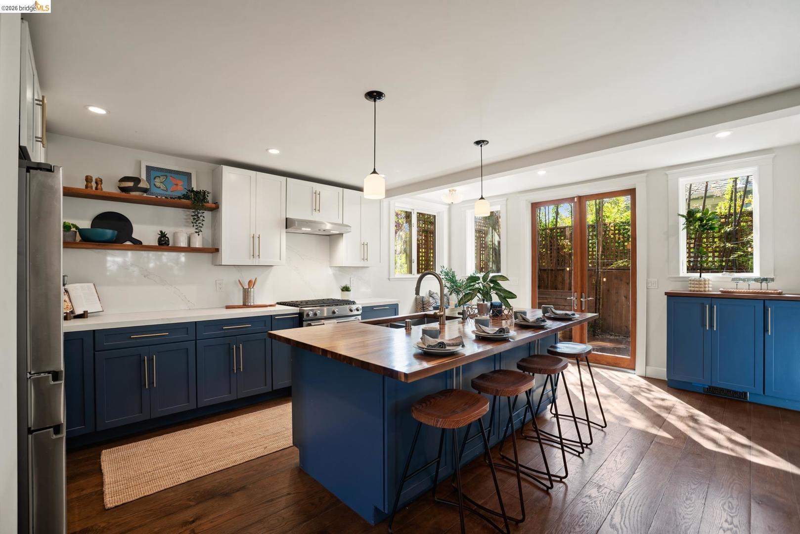 6145 Fremont Street — butcher-block island with four bar stools, open wood shelving and French doors to the back