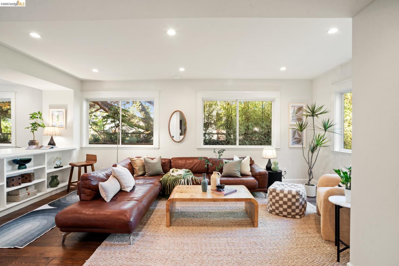 6145 Fremont Street — living room with a leather sectional, built-in shelves and windows onto the trees