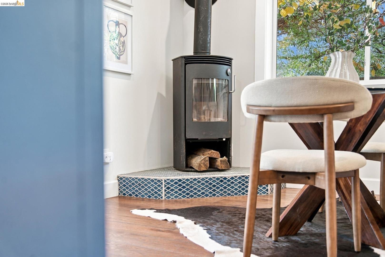 6145 Fremont Street — black wood-burning stove on a tiled hearth beside the dining table